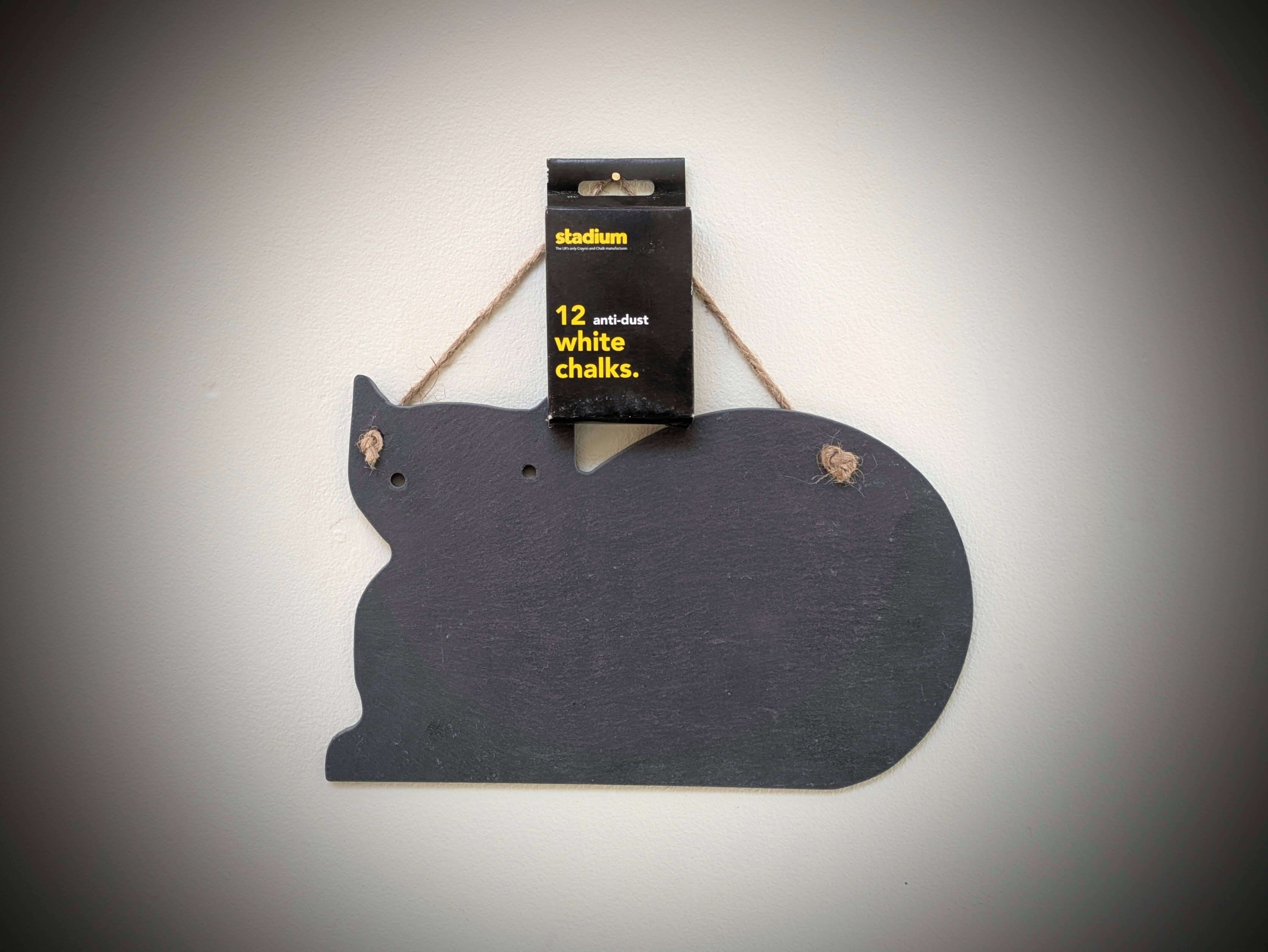 Cat-shaped blackboard with a box of white chalks on a gray background