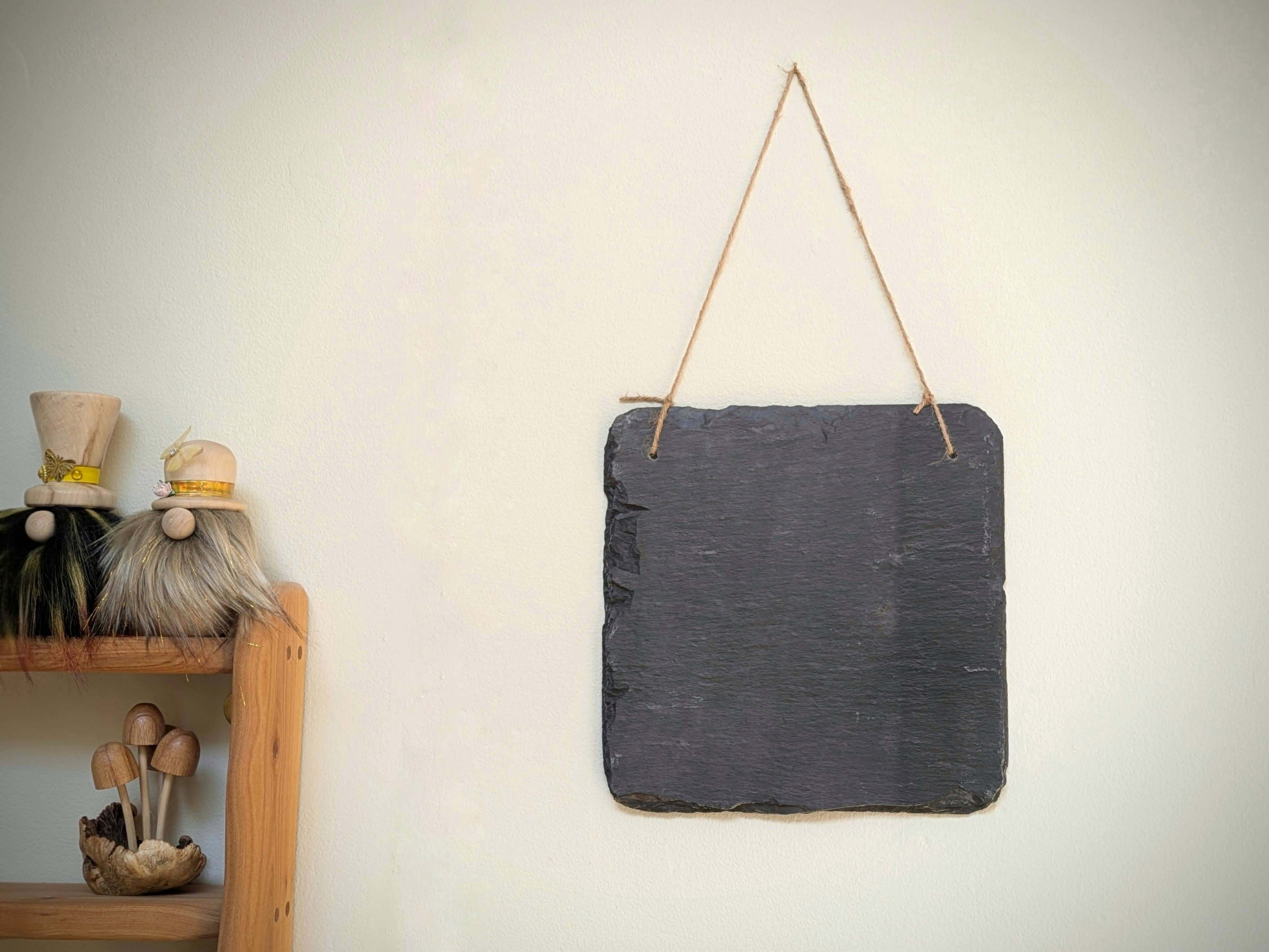 Slate board hanging on a wall with decorative elements below