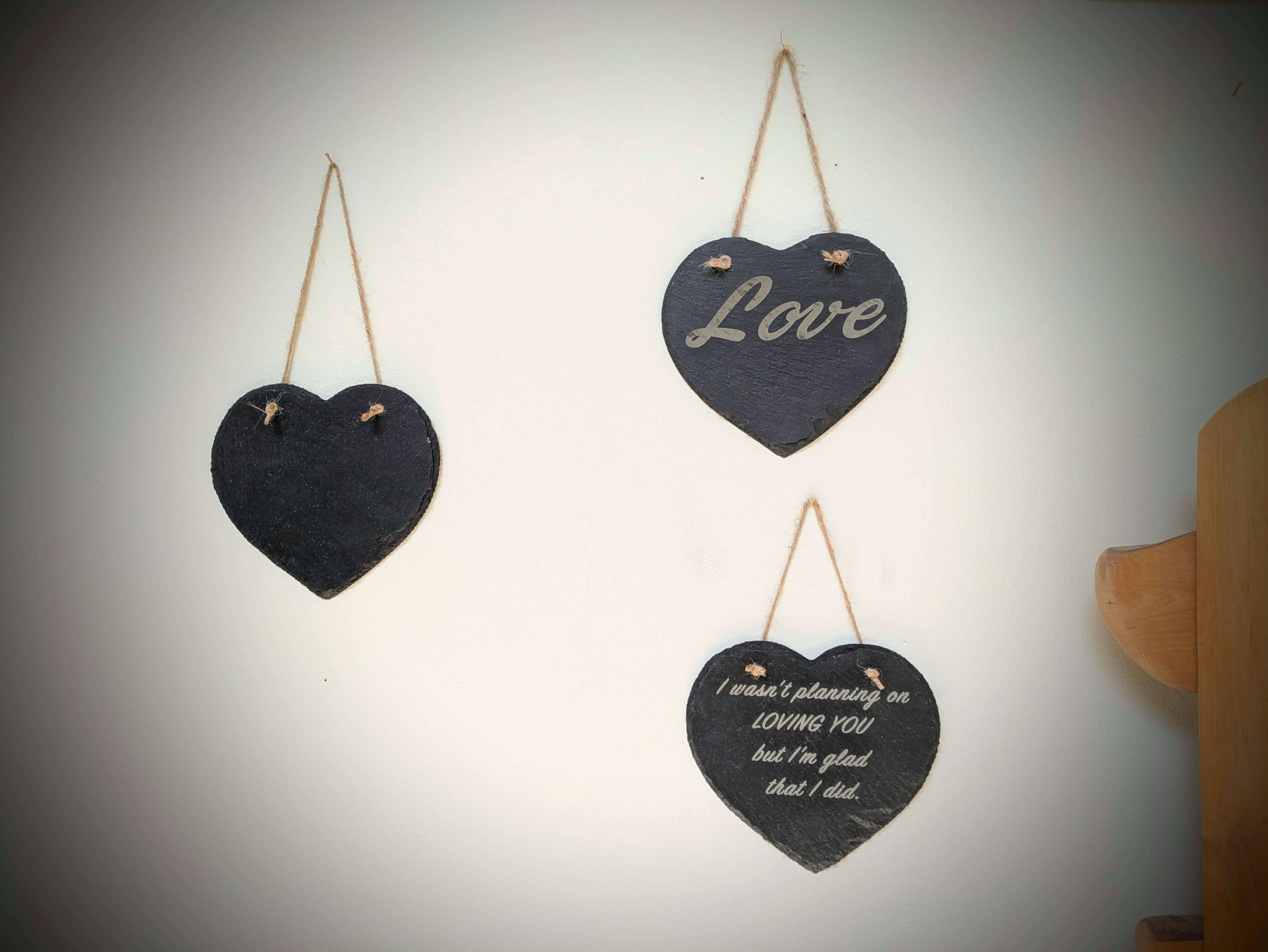 Three heart-shaped blackboards with text hanging on a wall.