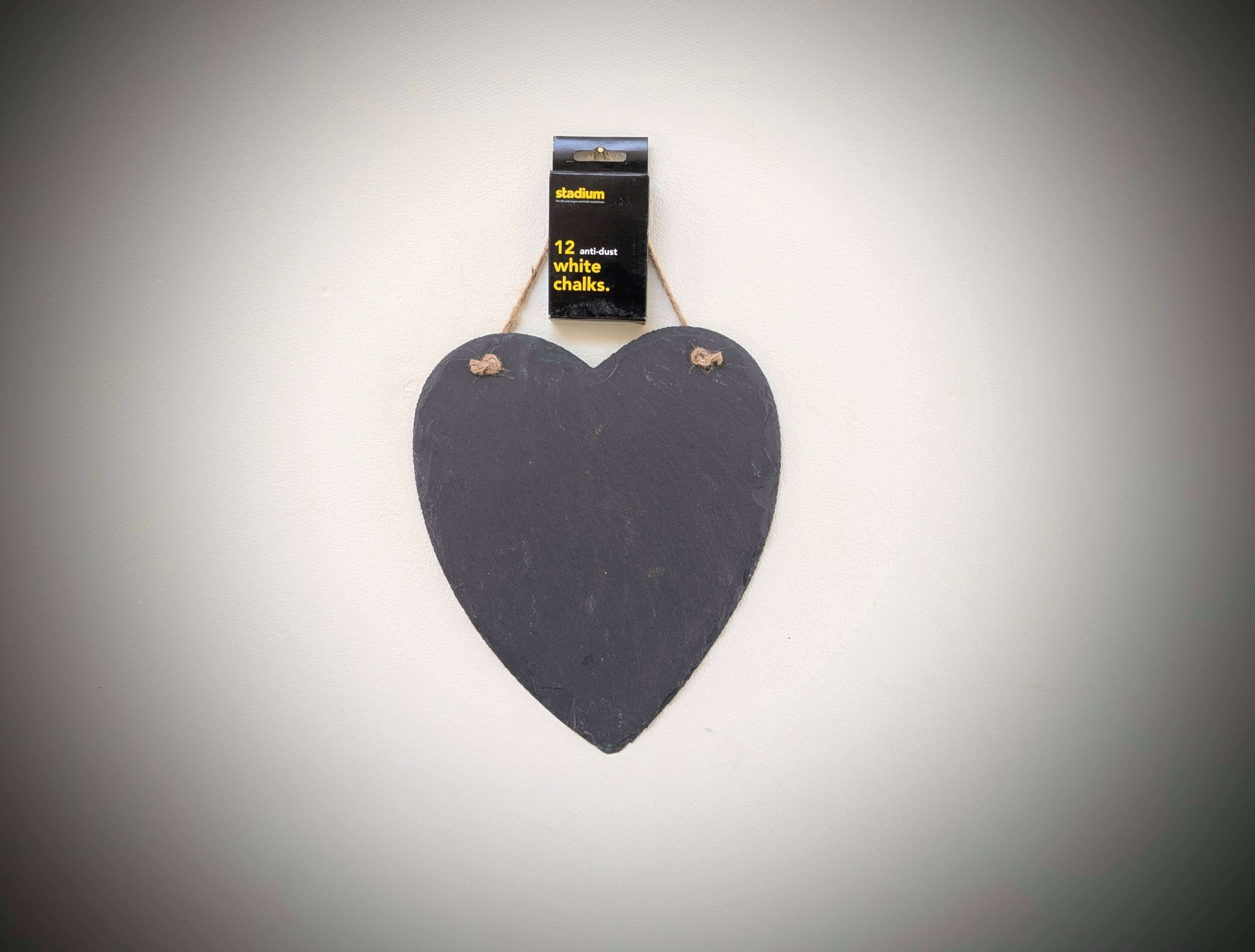 Heart-shaped chalkboard with a package of chalk on a gray background