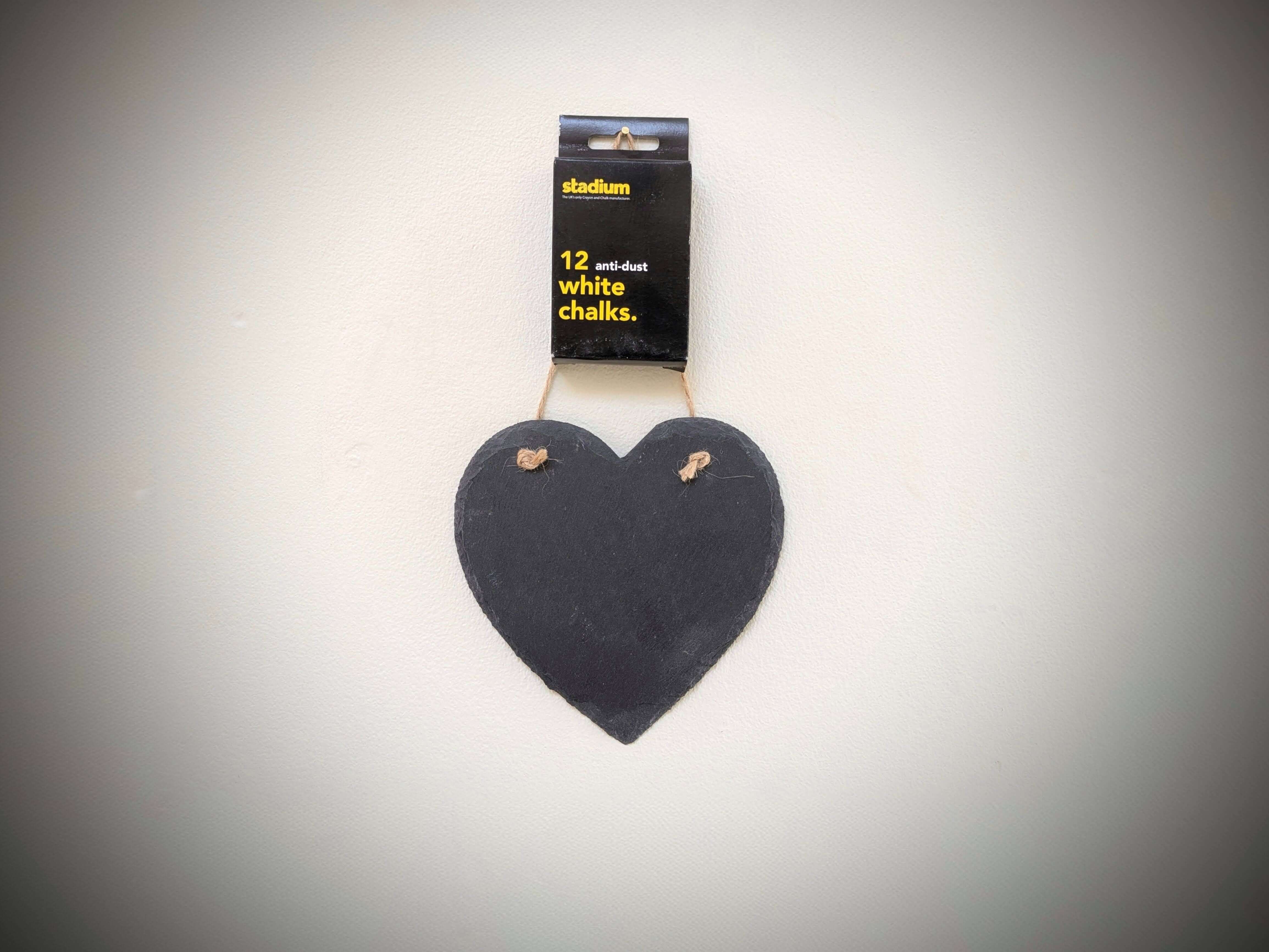 Heart-shaped blackboard with white chalks on a gray background